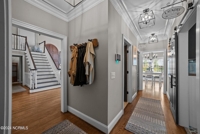 corridor with a barn door, a chandelier, crown molding, and wood finished floors