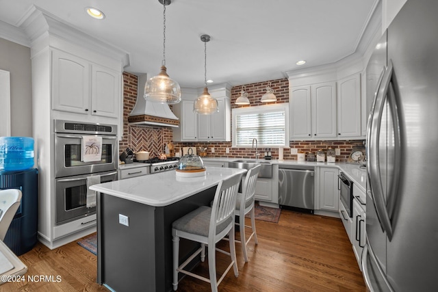 kitchen featuring appliances with stainless steel finishes, dark wood-type flooring, white cabinets, a sink, and a kitchen island