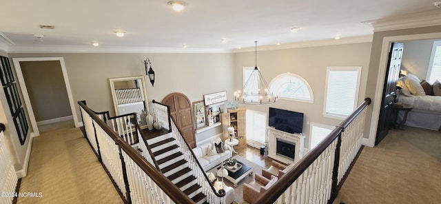 living room featuring light carpet, ornamental molding, a fireplace, and a notable chandelier