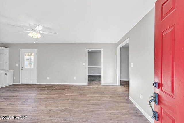 unfurnished room with baseboards, a ceiling fan, and light wood-style floors