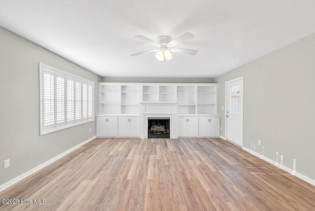 unfurnished living room with baseboards, plenty of natural light, a fireplace, and light wood-style floors