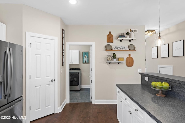 kitchen featuring stainless steel fridge with ice dispenser, dark countertops, washer / clothes dryer, dark wood-type flooring, and white cabinetry