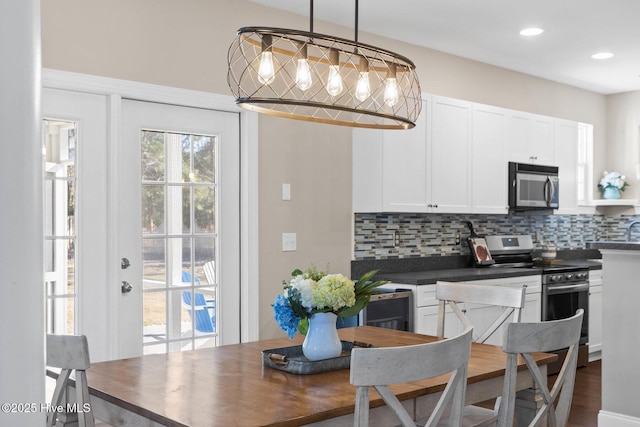 kitchen with appliances with stainless steel finishes, dark countertops, backsplash, and white cabinets