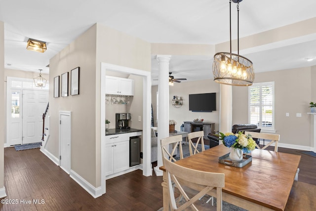 dining space with ceiling fan, wine cooler, dark wood-type flooring, baseboards, and ornate columns