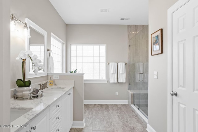 full bathroom with double vanity, a stall shower, plenty of natural light, and a sink