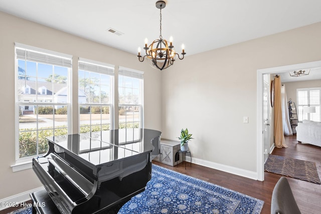 living area featuring an inviting chandelier, baseboards, visible vents, and wood finished floors