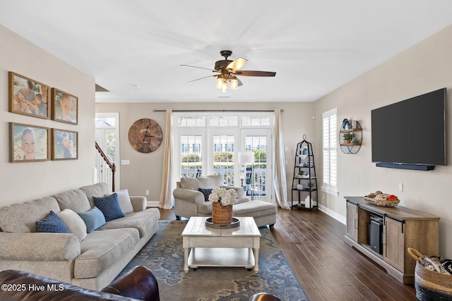 living area featuring ceiling fan, stairs, baseboards, and dark wood-style flooring