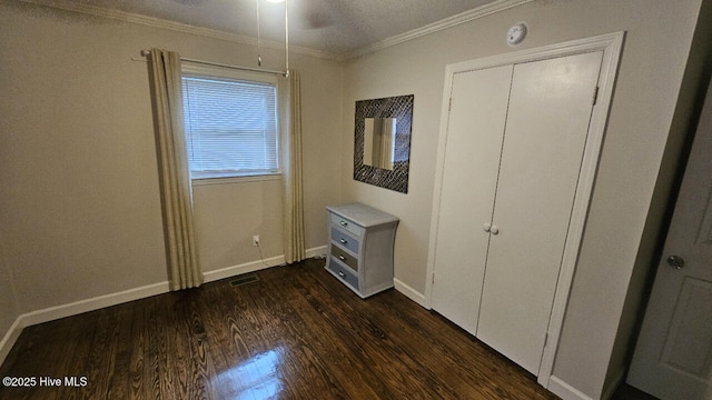 unfurnished bedroom with visible vents, baseboards, ornamental molding, and dark wood-style flooring