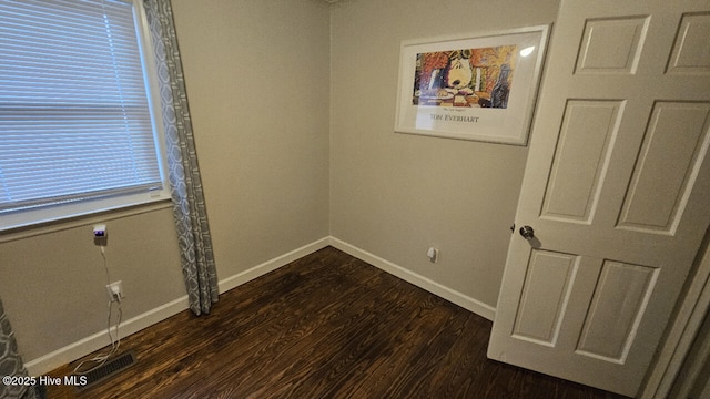 empty room featuring visible vents, baseboards, and dark wood-style floors