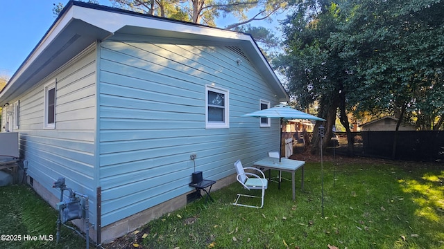 view of property exterior featuring a lawn, fence, and crawl space