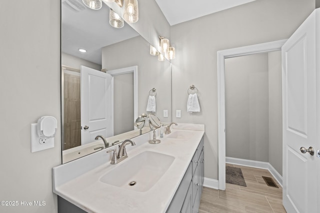 bathroom featuring a sink, baseboards, and double vanity