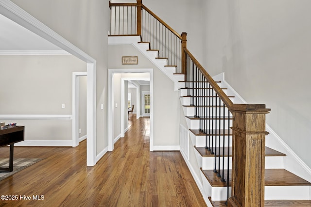 entryway featuring stairs, a high ceiling, wood finished floors, and baseboards