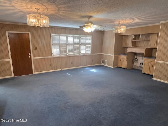 unfurnished living room featuring a textured ceiling, dark colored carpet, ornamental molding, and visible vents