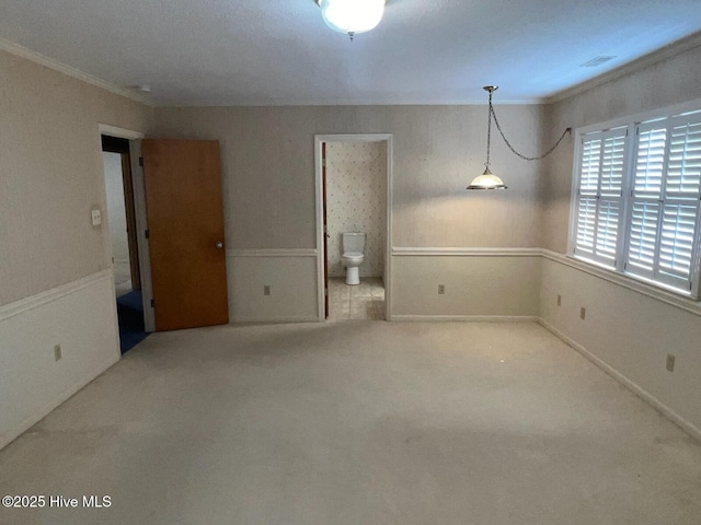 carpeted empty room featuring visible vents, ornamental molding, and baseboards