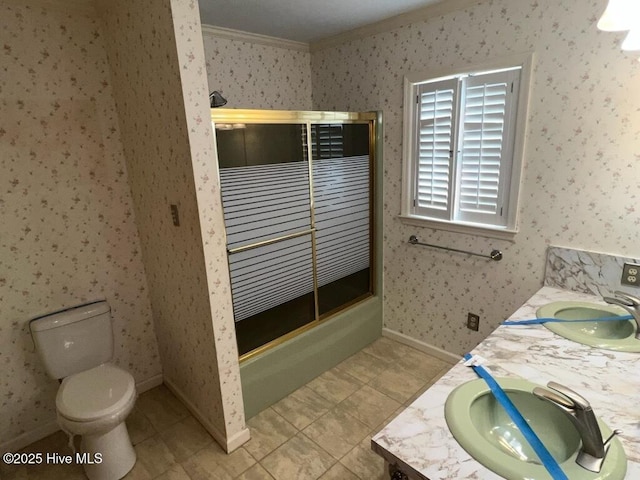 bathroom featuring double vanity, a sink, toilet, and wallpapered walls