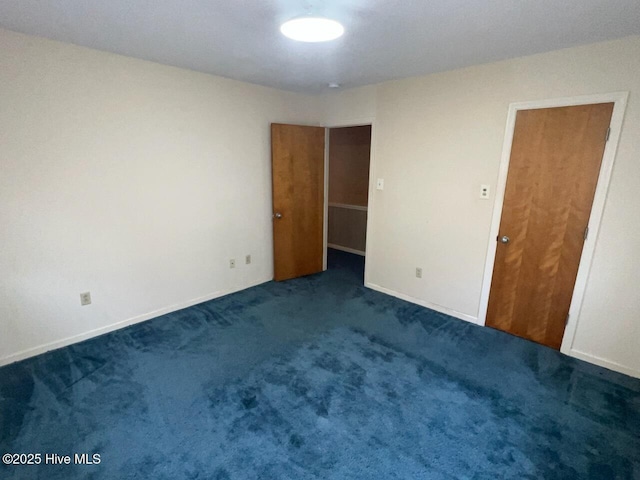 spare room featuring dark colored carpet and baseboards