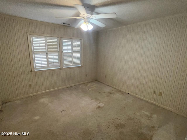 empty room with ceiling fan, carpet floors, visible vents, and baseboards