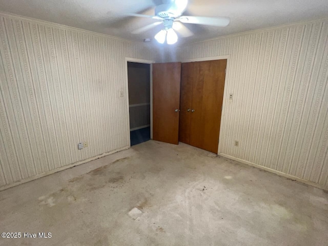 unfurnished bedroom featuring carpet floors, wallpapered walls, ceiling fan, and ornamental molding