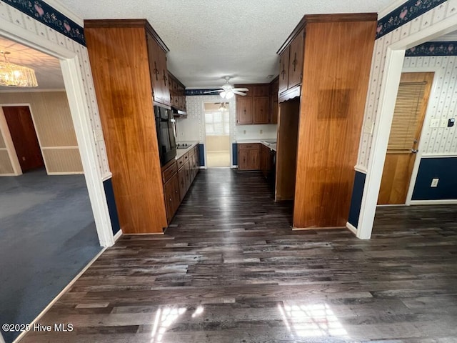 kitchen with dark wood-type flooring, a textured ceiling, and wallpapered walls