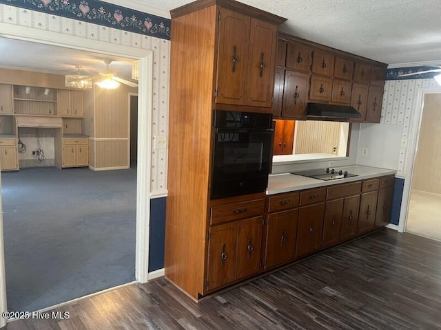 kitchen featuring black appliances, dark wood-style flooring, under cabinet range hood, and wallpapered walls