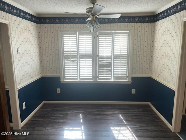 unfurnished dining area featuring a wainscoted wall, a textured ceiling, wood finished floors, and wallpapered walls