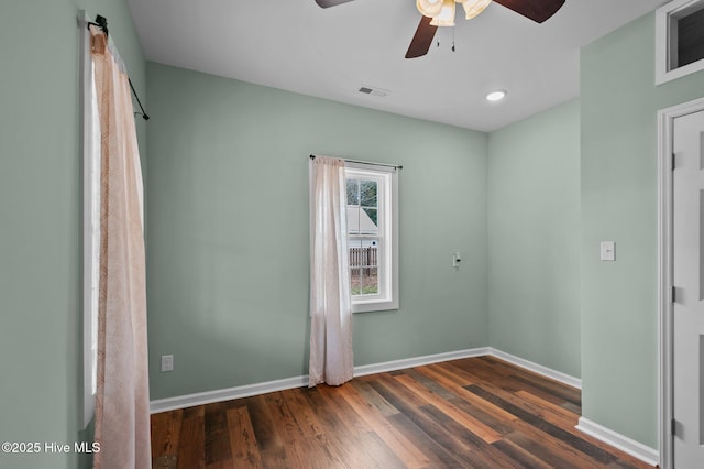 empty room featuring baseboards, visible vents, dark wood-style flooring, and ceiling fan