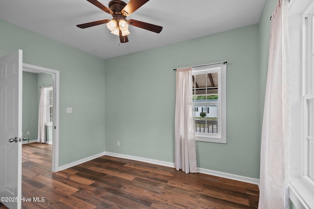 empty room with dark wood-style floors, baseboards, and ceiling fan