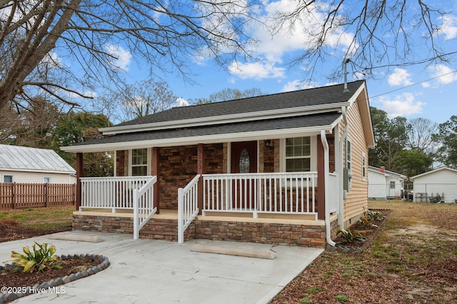 view of front facade with fence, covered porch, and roof with shingles