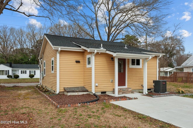 bungalow featuring a front yard, fence, central AC, and a shingled roof