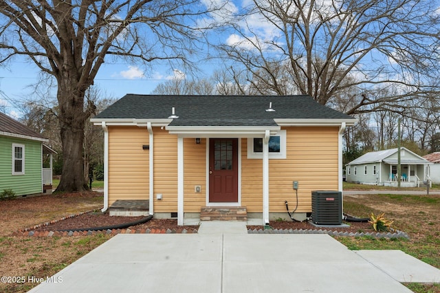 bungalow-style house with cooling unit and roof with shingles