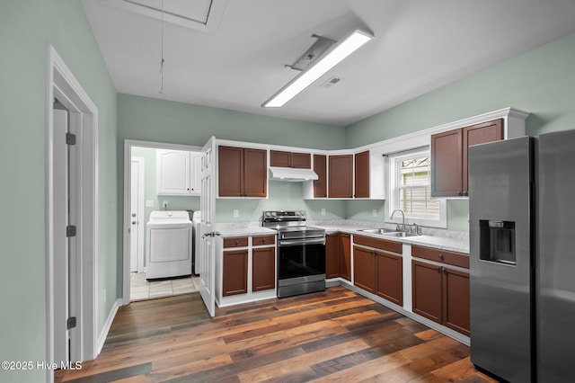 kitchen with dark wood finished floors, a sink, stainless steel appliances, light countertops, and under cabinet range hood