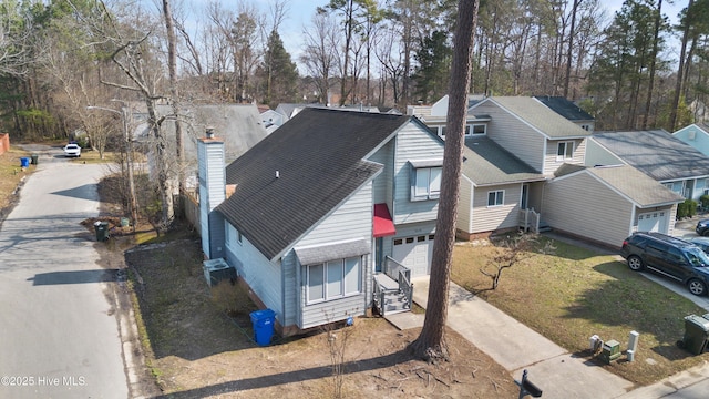 view of front facade featuring central AC, driveway, a chimney, and roof with shingles