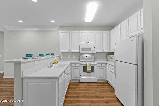 kitchen with light countertops, white cabinetry, a sink, white appliances, and a peninsula