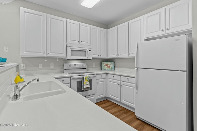 kitchen with white appliances, dark wood-style flooring, a sink, and white cabinetry