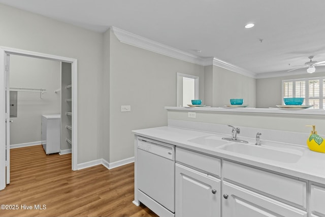 kitchen with washer / dryer, dishwasher, ornamental molding, light wood-style floors, and a sink