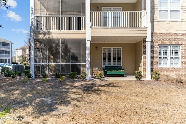 view of exterior entry featuring brick siding and a balcony