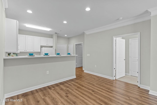 kitchen featuring baseboards, white cabinets, freestanding refrigerator, light wood-type flooring, and recessed lighting