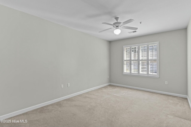 carpeted empty room featuring baseboards, visible vents, and a ceiling fan