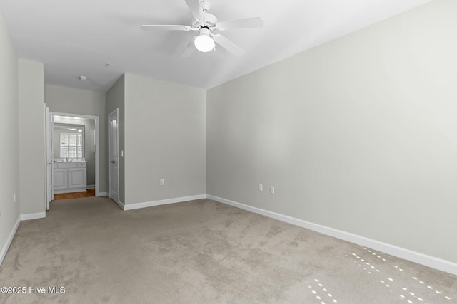 unfurnished room with a ceiling fan, light carpet, and baseboards