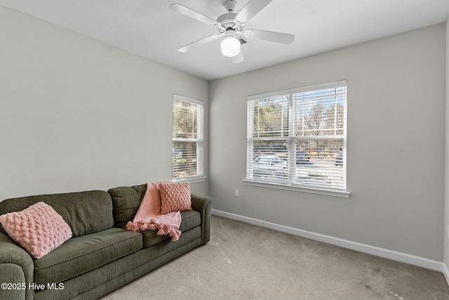 living area with a ceiling fan, baseboards, and carpet flooring