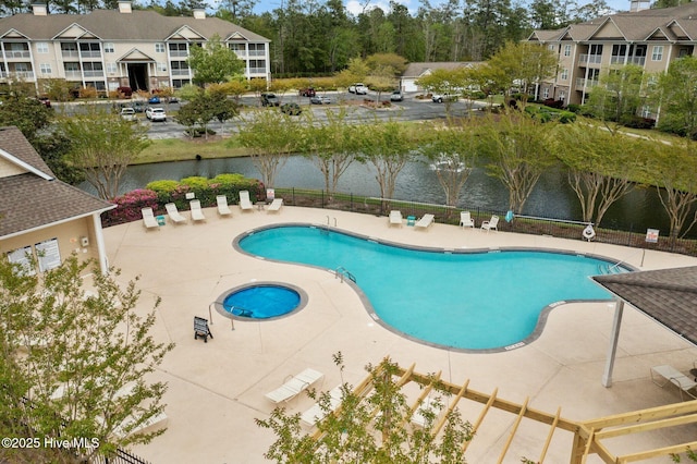 community pool featuring a water view, a patio area, and fence