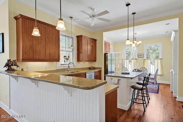 kitchen featuring a kitchen island, appliances with stainless steel finishes, brown cabinets, crown molding, and a sink