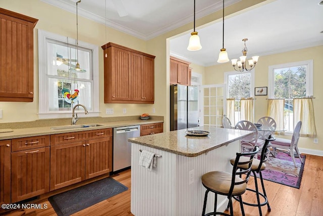 kitchen featuring a breakfast bar area, stainless steel appliances, a sink, light wood finished floors, and crown molding