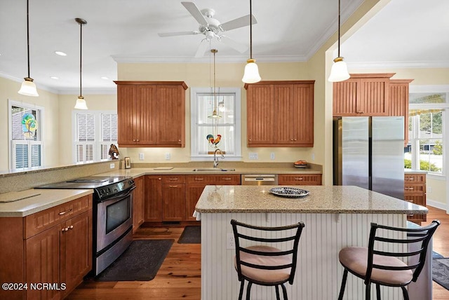 kitchen with ornamental molding, dark wood-type flooring, a peninsula, stainless steel appliances, and a sink