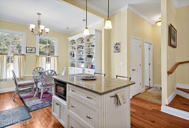 kitchen with black microwave, a center island, open shelves, light wood finished floors, and crown molding