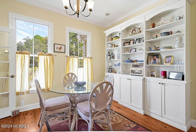 dining area featuring ornamental molding, light wood finished floors, and an inviting chandelier