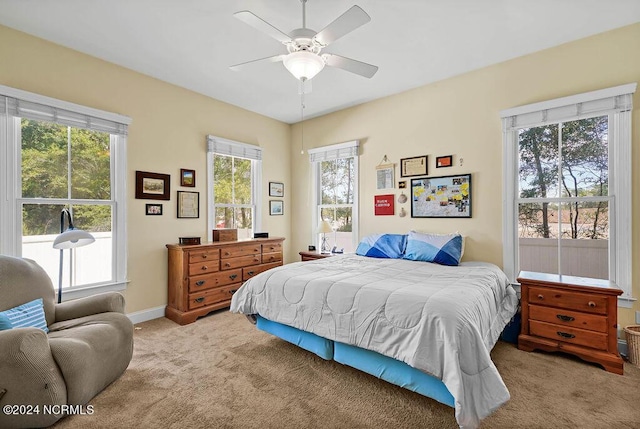 carpeted bedroom with multiple windows, ceiling fan, and baseboards