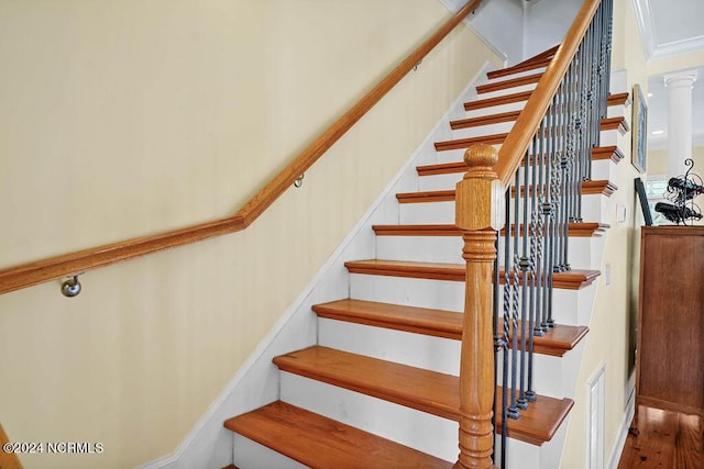 staircase with decorative columns, visible vents, and wood finished floors