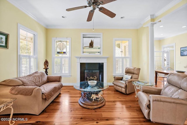 living area featuring a tile fireplace, crown molding, ornate columns, and wood finished floors