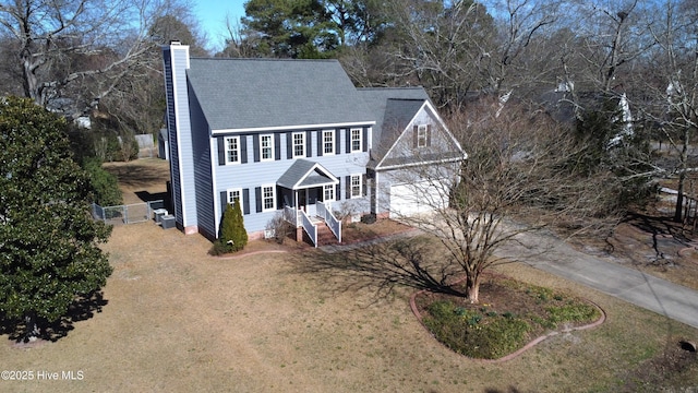 colonial inspired home featuring concrete driveway, fence, and a chimney